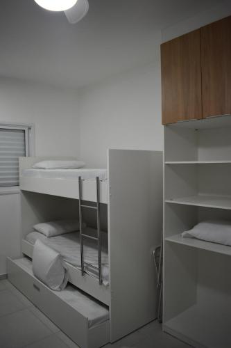 Dieses weiße Zimmer verfügt über ein Etagenbett und Regale. in der Unterkunft Apartamento próximo a Canção Nova in Cachoeira Paulista