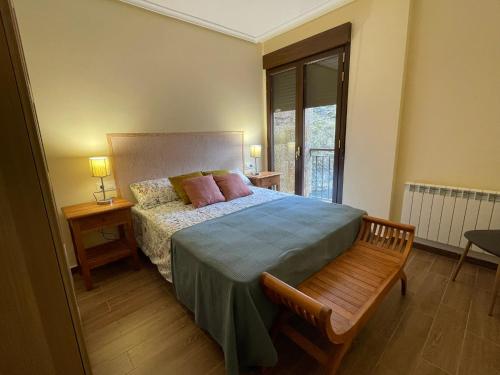1 dormitorio con cama, banco y ventana en Moradas Portilla, en Portilla de la Reina