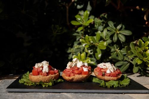 three pieces of bread with tomatoes and cheese on a plate at Iria Beach Art Hotel in Agia Anna Naxos