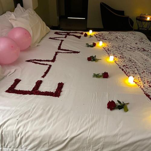 a birthday cake on a bed with candles and roses at فندق السلطنة جازان -Alsltanah Jazan Hotel in Jazan