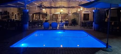 a swimming pool with blue lighting in a building at Marrakech Guest House in Bloemfontein