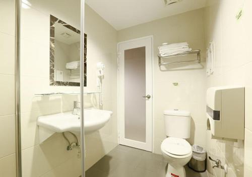 a white bathroom with a toilet and a sink at Hua Xiang Motel - Arena in Kaohsiung