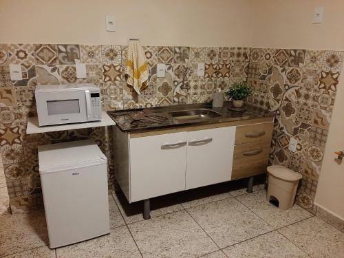 una cocina con fregadero y microondas en una encimera en Residencial Villàggio Toscana, en Sorocaba