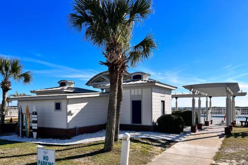 a white building with a palm tree next to a sidewalk at Plantation East #3219 in Gulf Highlands