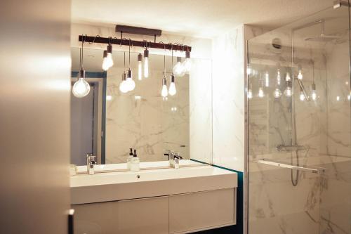 uma casa de banho branca com um lavatório e um chuveiro em Charlie et la Chocolaterie- Parking- Clim- CentreVille em Montauban