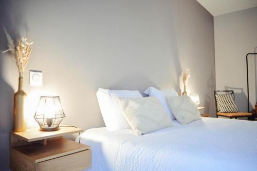 a bedroom with a bed with white sheets and a lamp at Charlie et la Chocolaterie- Parking- Clim- CentreVille in Montauban