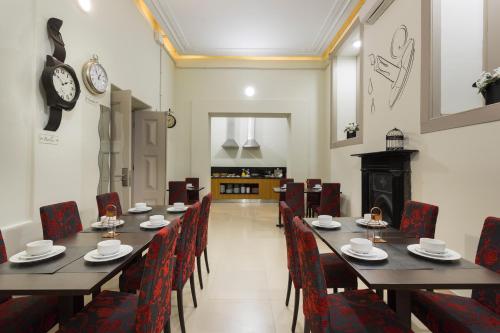 Serenata Hotel & Hostel Coimbra في كويمبرا: غرفة طعام مع طاولات وكراسي وساعة