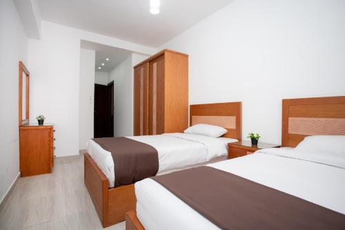 two beds in a hotel room with white walls at Lazur Sea & City Apartment's - El Hadaba, Hurghada - Egypt in Hurghada