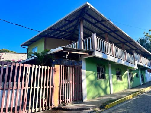 una casa verde y blanca con una valla de madera en Hotel Pacific Surf AC Room Best in Tunco Beach en Tamanique