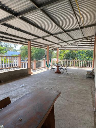 eine große Terrasse mit einem Holztisch und einer Hängematte in der Unterkunft Hotel Pacific Surf AC Room Best in Tunco Beach in Tamanique