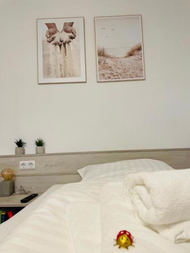 バート・グリースバッハにあるFeWo 20 - Appartement im Rottalblick - YoungModern wohnen, Tiere willkommen, Bademantelgang zur Therme, TV und Balkonのベッドと壁に2枚の絵が飾られた寝室