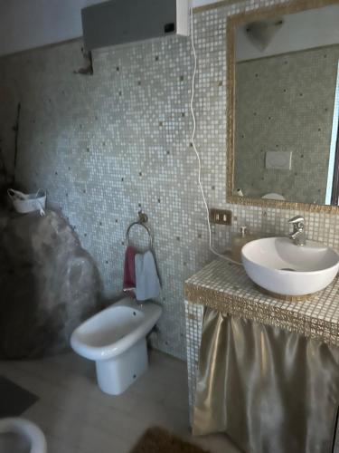 W łazience znajduje się umywalka, toaleta i lustro. w obiekcie Locanda verde w mieście Vaiano