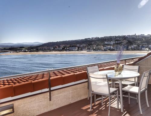 una mesa y sillas en un balcón con vistas al océano en Apartamento Faro de Suances, en Suances