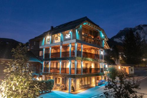 un grand bâtiment avec des lumières allumées la nuit dans l'établissement Alpine Residence Villa Adler, à San Vigilio Di Marebbe