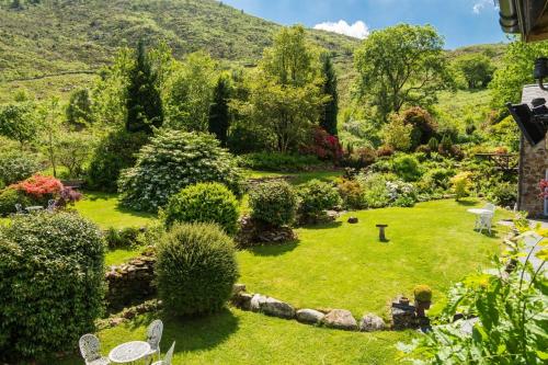 ogród z trawnikiem z krzesłami i drzewami w obiekcie Sygun Fawr Country House w mieście Beddgelert