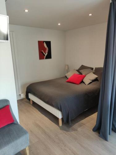 - une chambre avec un lit doté d'oreillers rouges et d'une chaise dans l'établissement TRESTRIGNEL MAGNIFIQUE VUE MER. Studio à PERROS-GU, à Perros-Guirec