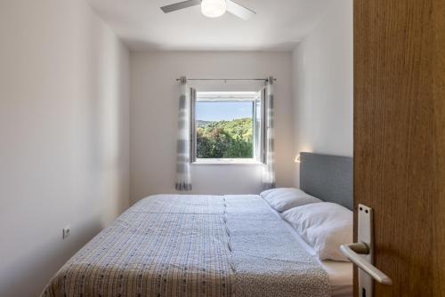 1 dormitorio con cama y ventana en Apartment Jagoda, en Postira