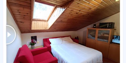 um quarto com uma cama branca e um sofá vermelho em [Aprica 4 min. piste baradello] em Aprica