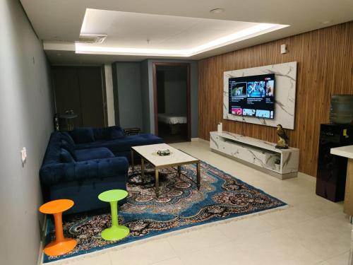 uma sala de estar com um sofá azul e uma televisão em Fun Bedroom Apartment in Gold Crest Mall and Residency DHA Lahore em Lahore