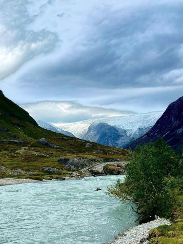 a river in a valley with snow covered mountains at Tungestølen in Veitastrond