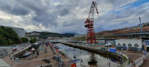 a river with a crane next to a stadium at Bilbao, a un paso. in Bilbao