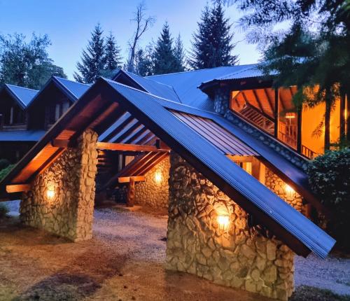 a house with a stone wall and a gambrel roof at Altos Los Pioneros & Spa in Villa La Angostura