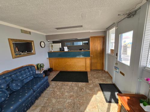 a living room with a blue couch and a kitchen at Richmond Inn and Suites in Richmond