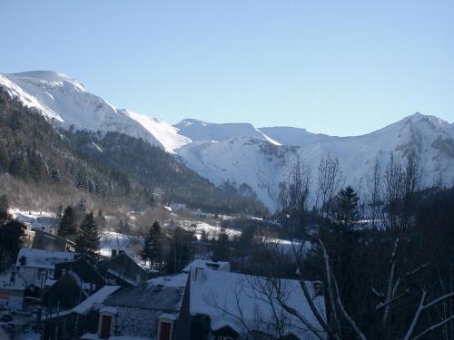 a village with snow covered mountains in the background at Hôtel de Londres in Le Mont-Dore