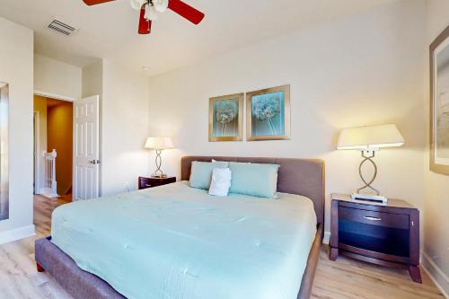 a bedroom with a bed with blue sheets and two lamps at Retreat Magic in Orlando