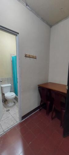 baño con aseo, mesa y piano en Hotel Villas de San Juan, Guatemala, en Guatemala