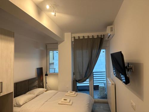 a bedroom with a bed and a tv and a window at Brand new studios IPM1-2-3-4 in Larisa