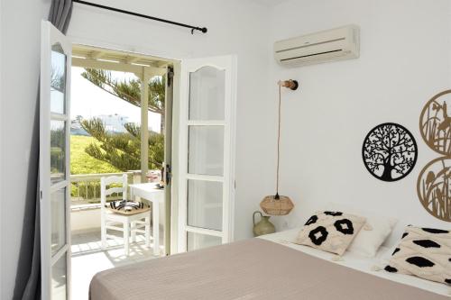 a bedroom with a bed and a balcony with a table at Aegean White Aparts in Naxos Chora