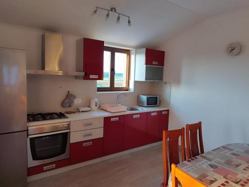 a kitchen with red cabinets and a stove top oven at Nika's Sea View Oasis in Seget