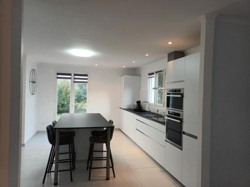 une cuisine avec des placards blancs et une table noire dans l'établissement Maison de Chamechaude, à Fontaine