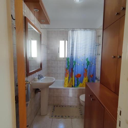 een badkamer met een wastafel en een douchegordijn bij Quiet holiday house near the beach in Menevi