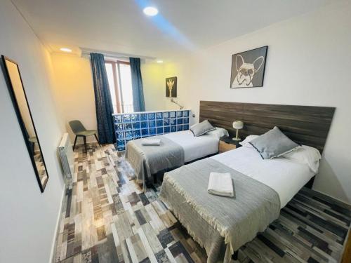 a hotel room with two beds and a chair at Acogedor apartamento en San Braulio in Zaragoza