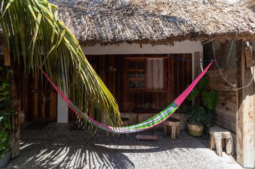 a hammock in front of a house with a thatch roof at Zayali Bacalar - Guest House in Bacalar