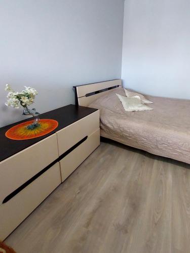 a bedroom with a bed and a dresser with a vase of flowers at Дво і одно кімнатні апартаменти новобуд рн авторинку трц Адреналін сіті in Luts'k