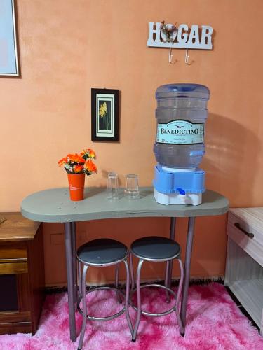 una mesa con dos taburetes y un enfriador de agua en ella en Amanda, en Calama