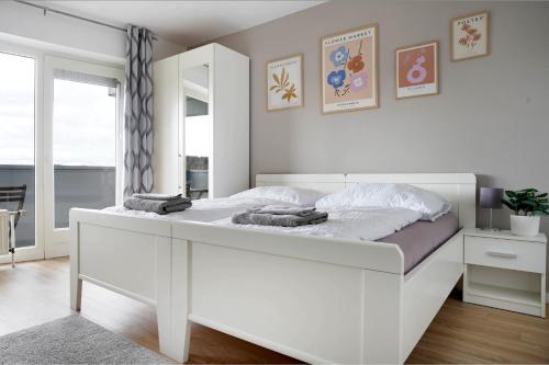 a white bed in a white bedroom with a window at Schöne Apartments in Bad Rothenfelde I private Parkplätze mit Ladesäulen I home2share in Bad Rothenfelde