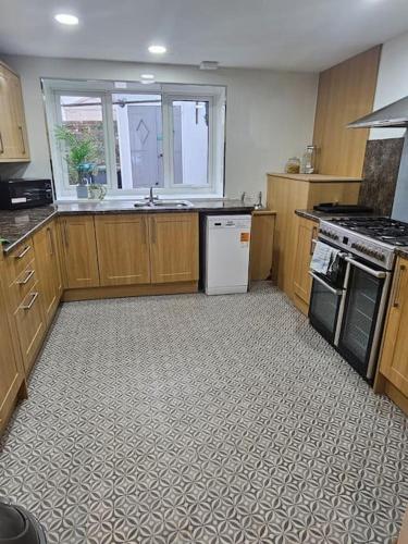 a kitchen with wooden cabinets and a stove top oven at HollyJess Hoose in Stranraer