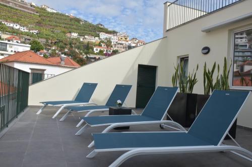 rząd niebieskich leżaków na balkonie w obiekcie Vicente´s LOB ( Lobos Ocean Breeze) w mieście Câmara de Lobos