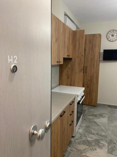 a kitchen with wooden cabinets and a door with a clock at Brand new studios Η1-Η2-Η3 in Larisa