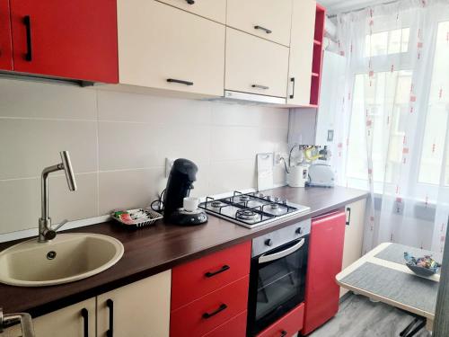 a kitchen with red and white cabinets and a sink at Feel Like Home in Piatra Neamţ