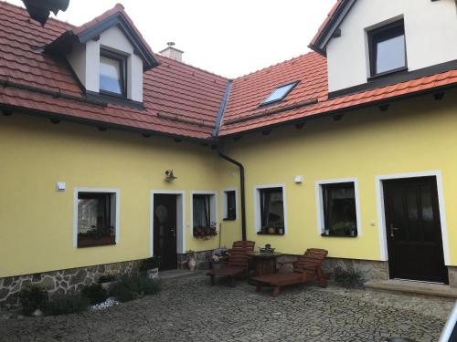 a yellow house with a patio with chairs and a table at Apartmán Dolánek in Jankov