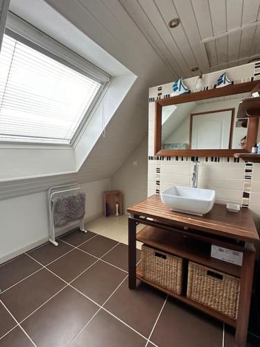 La salle de bains est pourvue d'un lavabo, d'une fenêtre et d'un miroir. dans l'établissement Penty Breton proche mer Beg Meil, à Fouesnant