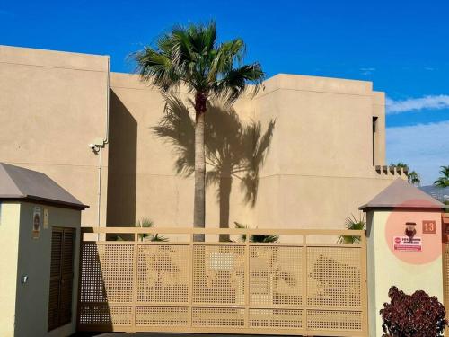 a building with a palm tree behind a fence at Sol & Mar in El Médano