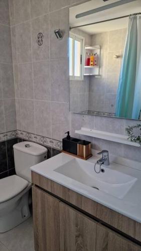a bathroom with a sink and a toilet and a mirror at Stunning sea vistas by the beach in Benicàssim