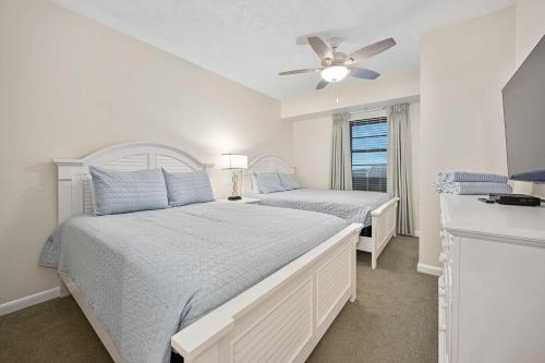 a white bedroom with two beds and a ceiling fan at Luxury 10th Floor 3 BR Condo Direct Oceanfront Wyndham Ocean Walk Resort Daytona Beach | 1011 in Daytona Beach
