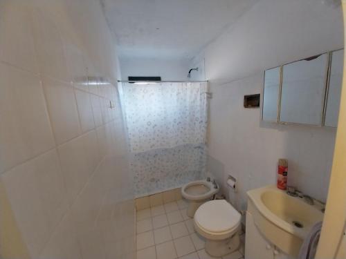a white bathroom with a toilet and a shower at Casita Mutisia in Neuquén